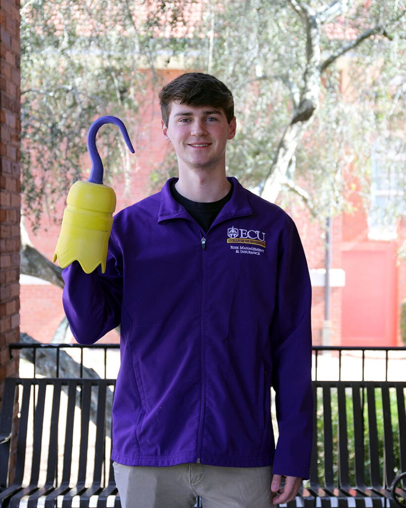 male student in a purple polo holding a 3D printed hook
