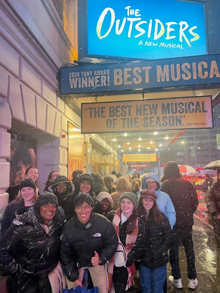 students standing in front of "The Outsiders" marquee sign