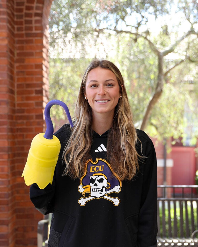 female student wearing black sweatshirt with ECU Athletics logo and holding a 3D printed hook