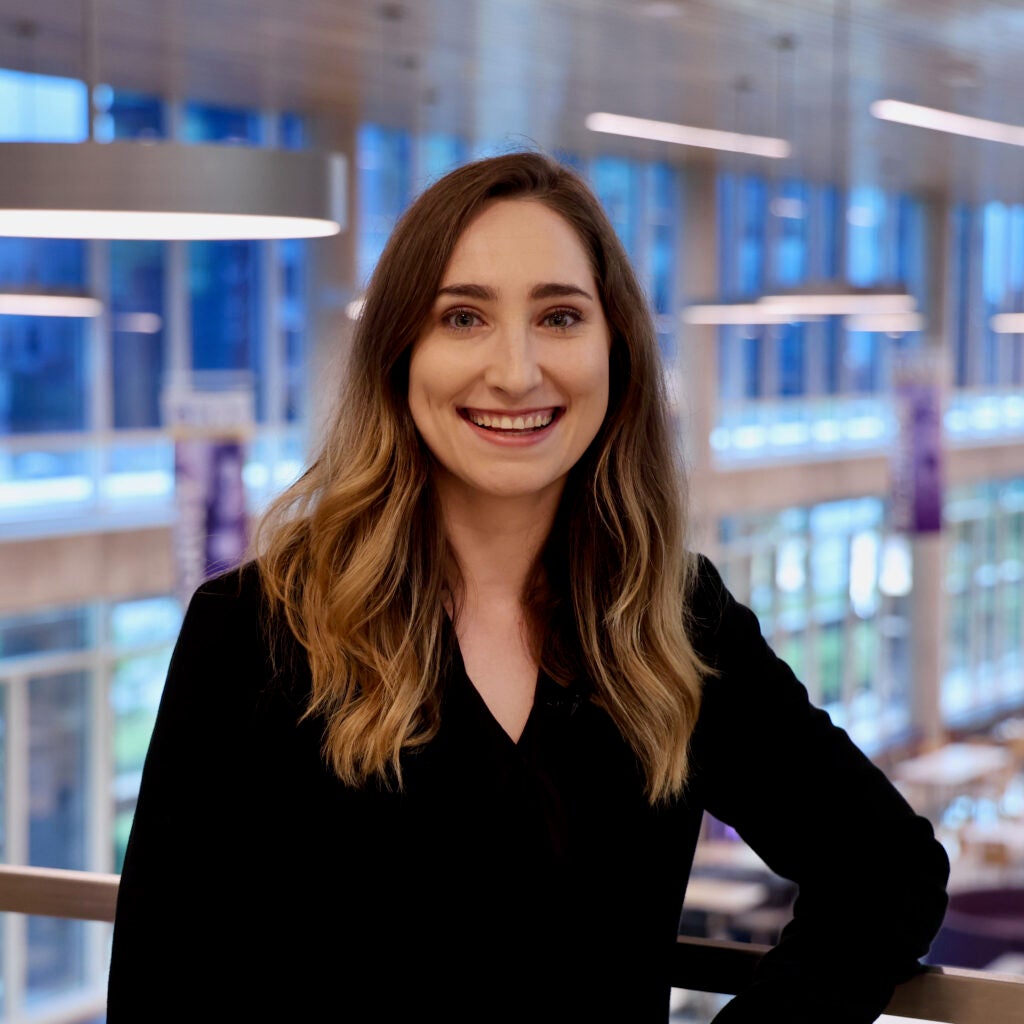 woman poses for photo in front of wall of windows