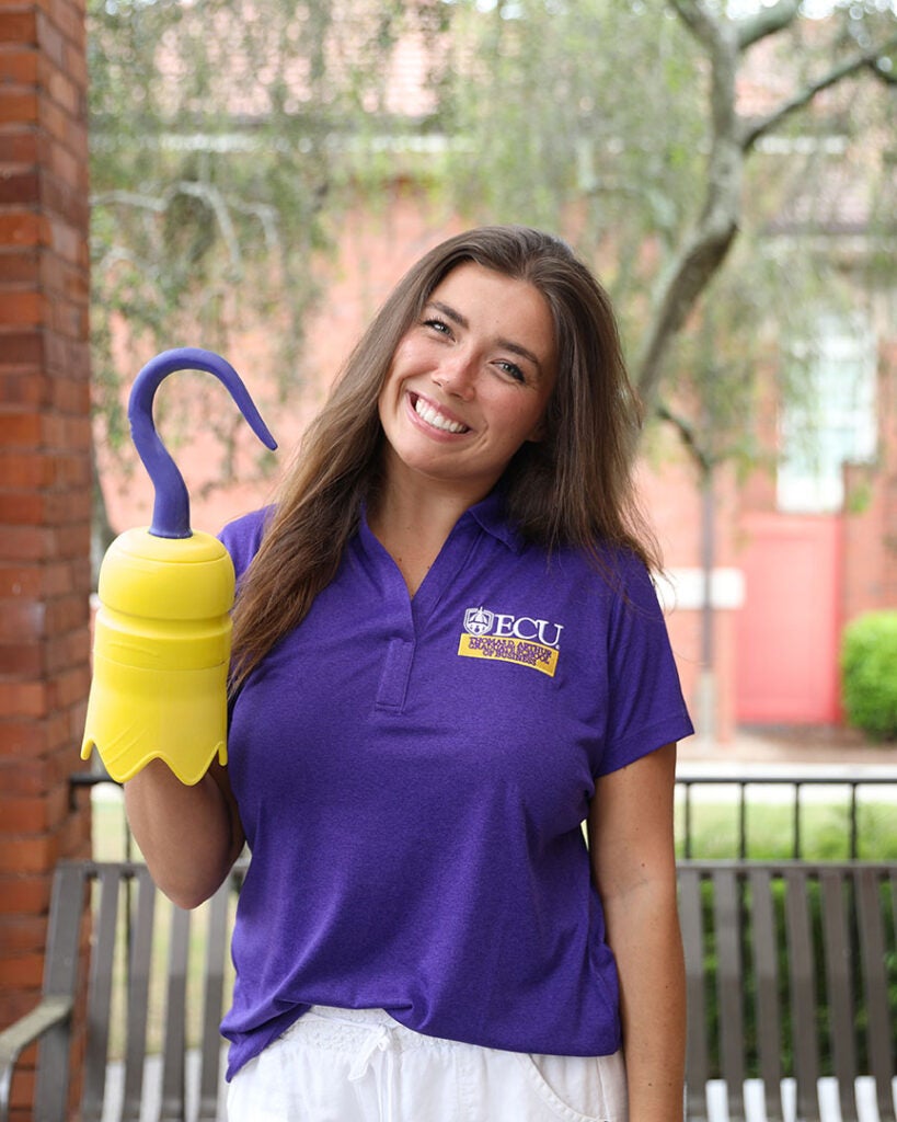 female student wearing a purple ECU polo and holding a 3D printed hook
