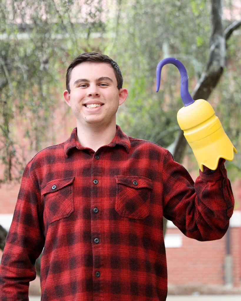 male student wearing a red and black flannel and holding a 3D printed hook