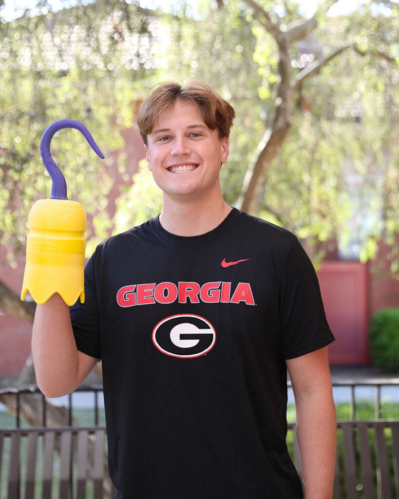 male student wearing a black tshirt with Georgia written on it and holding a 3D printed hook