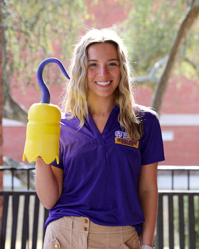 female student wearing a purple ECU polo and holding a 3D printed hook