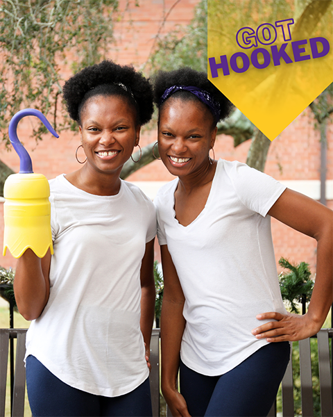 two female students. one holds a 3D printed hook