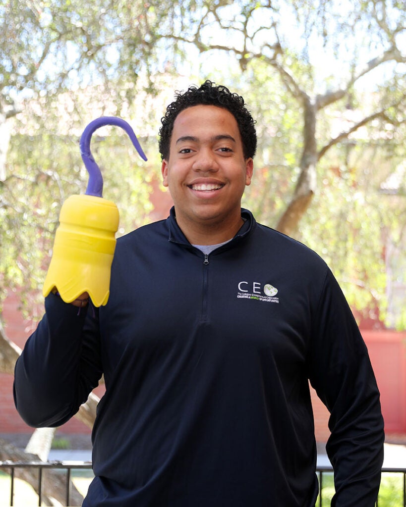 male student wearing a quarterzip with the CEO club logo and holding a 3D printed hook