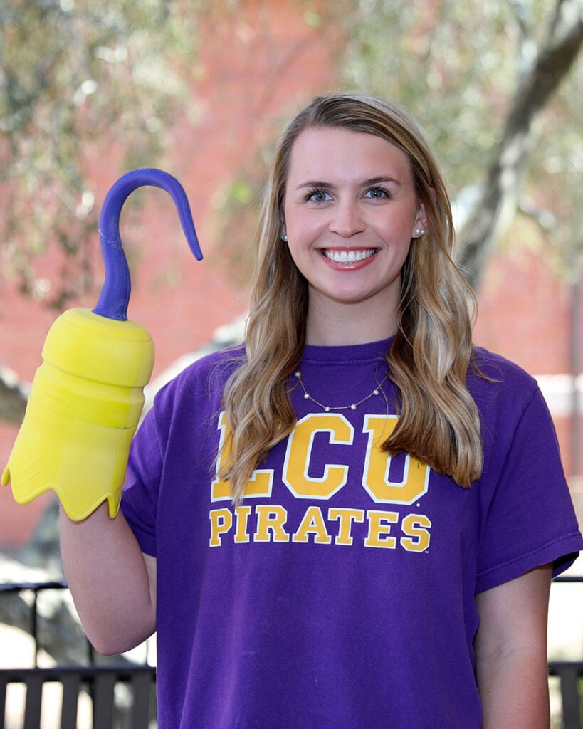 female student wearing a purple ECU Pirates shirt and holding a 3d printed hook