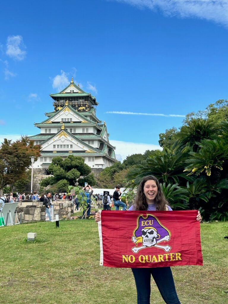 female student holding ECU No Quarter flag in Japan